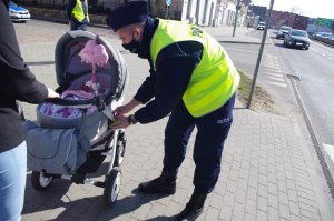 policjant przyczepia odblask do wózka dziecięcego