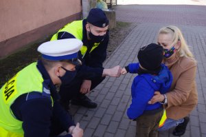 chłopiec przybija policjantowi tzw. żółwika, obok inny policjant i opiekunowie
