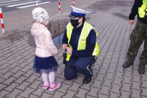 policjantka klęczy przy dziecku,  w tle droga