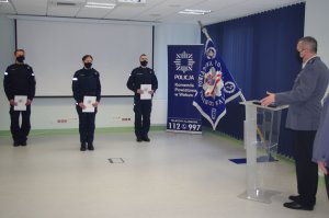 komendant przemawia do policjantów,  w tle sala