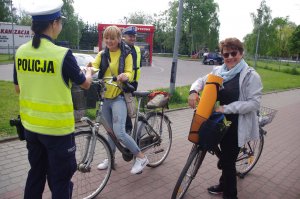 policjantka wręcza kamizelki,  w tle zabudowania