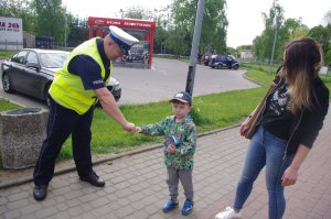 policjant przybija piąstkę z chłopce w tle zabudowania