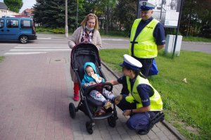 policjantka wręcza  dziecku odblask, w tle osiedle