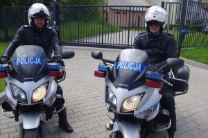 policjanci na motocyklach pozują do zdjęcia w tle ogrodzenie jednostki