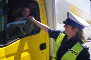 policjantka wręcza kierowcy niespodziankę, w tle samochód