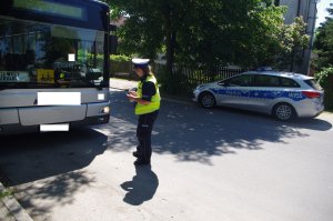 policjantka kontroluje autobus, w tle radiowóz