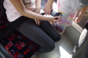 dziecko zapina pas bezpieczeństwa, w tle wnętrze autobusu