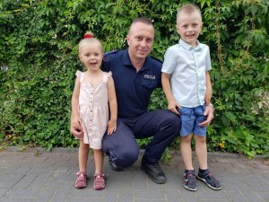 umundurowany policjant i jego dzieci, w tle roślinność