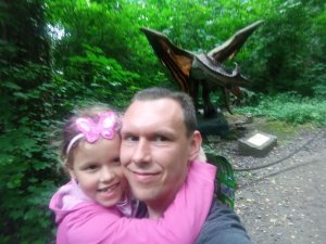 tata policjant trzyma dziecko na rękach w tle zieleń i dinozaur