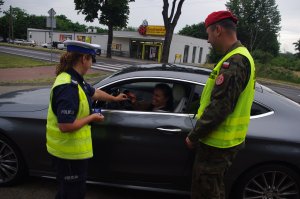 policjantka i żandarm rozmawia z kierowcą  w tle auto