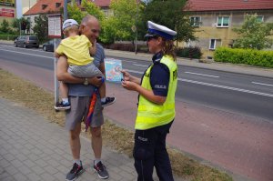 policjanta i mężczyzna trzymający na rękach dziecko, w tle ulica