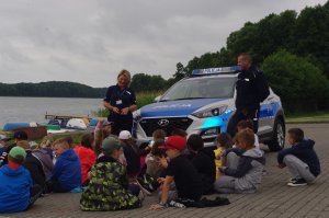 dzieci i policjanci w tle jezioro