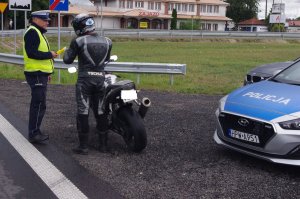 policjant sprawdza stan trzeźwości u kierującego motocyklem w tle ulica