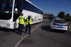 policjantki kontrolują autobus   w tle zabudowania