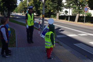 dzieci i policjantka przy sygnalizatorze, w tle ulica