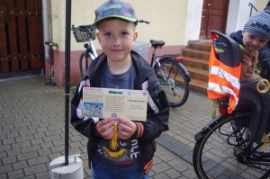 chłopiec trzyma w ręce mini kartę rowerową,  w tle rowery