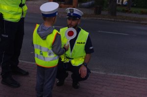 policjant rozmawia z chłopcem,  w tle ulica
