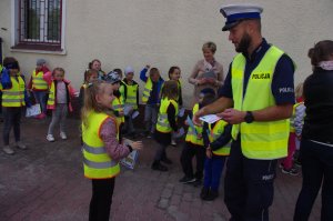 policjant wręcza dziecku dyplom  w tle dzieci