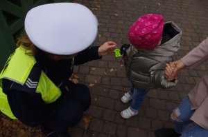 policjantka wręcza odblask dziecku w tle cgodnik
