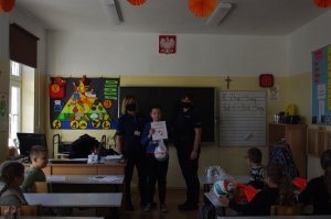 policjantki wręczają nagrody uczniom w tle sala lekcyjna