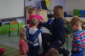 policjantka zakłada dzieciom odblaskowe szelki