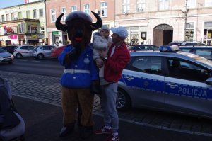 policjantka wręcza dziecku niespodziankę w tle żubrzyk i ulica