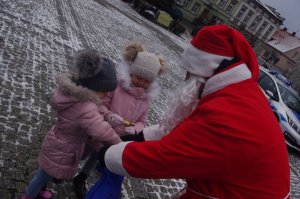 Mikołaj częstuje dzieci cukierkami w tle miasto