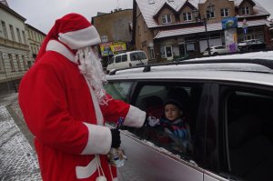 Mikołaj rozmawia z dzieckiem w aucie w tle miasto