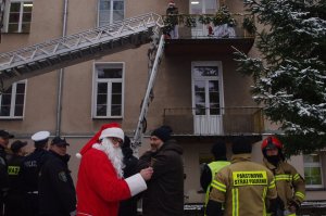 Mikołaj na terenie szpitala,  w tle budynek i wóz  strażacki