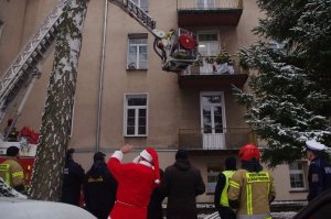 Mikołaj na terenie szpitala,  w tle budynek i wóz  strażacki