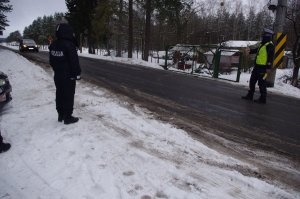 policjant zatrzymuje pojazd, w tle zaśnieżone drogi
