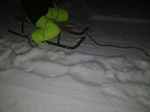 dziecko na sankach,  w tle śnieg