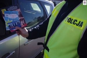 policjant prezentuje ulotki w tle auto