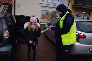 policjantki wręczają dzieciom pamiątki w tle auto
