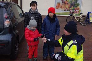 policjantki wręczają dzieciom pamiątki w tle auto