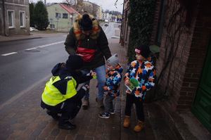 policjantki wręczają dzieciom pamiątki w tle ulica