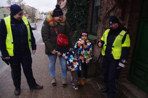 policjantki wręczają dzieciom pamiątki w tle ulica