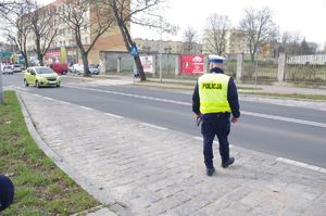policjanci kontrolują ruch drogowy w tle ulica i zabudowania