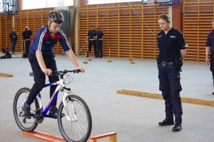 policjanci oceniają test sprawnościowy uczestnika w tle hala