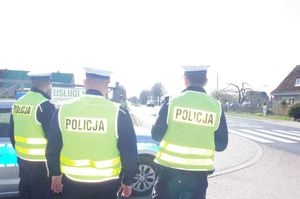 policjant sprawdza prędkość, w tle ulica i pojazdy