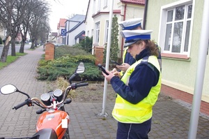 policjantka kontroluje motocyklistę, w tle zabudowania