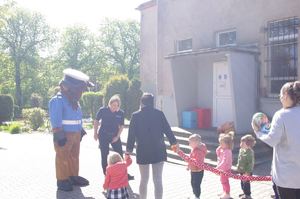 policjantka i policyjna maskotka rozmawia z dziećmi  w tle teren przedszkola