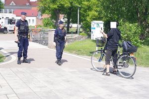 policjanci rozmawiają z rowerzystą, w tle promenada jeziora