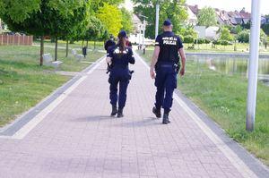 policjanci rozmawiają z rowerzystą, w tle promenada jeziora