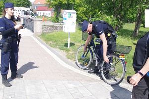 policjanci rozmawiają z rowerzystą, w tle promenada jeziora