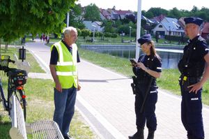 policjanci rozmawiają z rowerzystą, w tle promenada jeziora