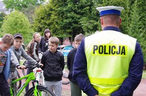 policjant egzaminuje rowerzystę w tle rowerzysta i plac szkolny