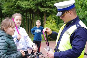 policjant egzaminuje rowerzystę w tle rowerzysta i plac szkolny