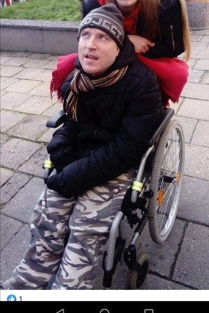 mężczyzna niepełnosprawny na wózku inwalidzkim w tle chodnik