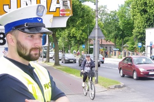 policjanci rozmawiają z rowerzystami w tle ulica